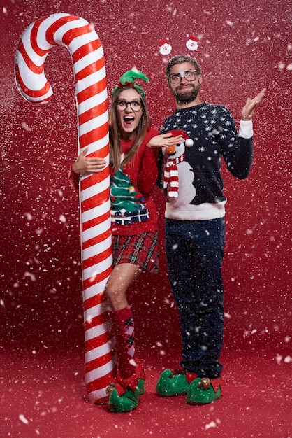 Abundancia de nieve en Navidad con pareja de pie junto al bastón de caramelo