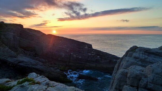 Acantilados rodeados por el mar bajo la luz del sol durante la puesta de sol