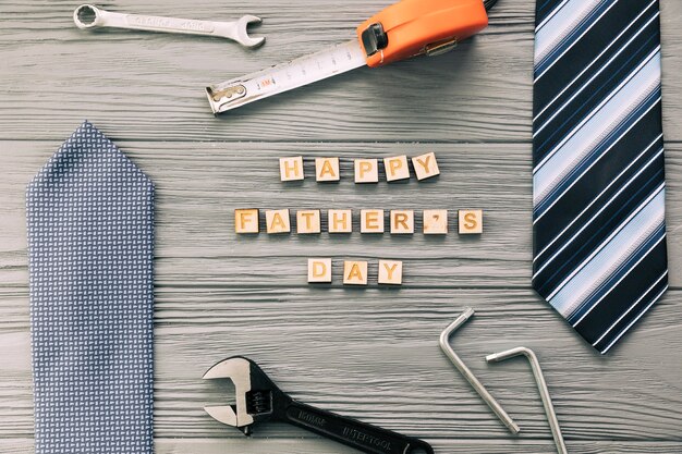 Accesorios masculinos cerca de instrumentos y felices palabras del día del padre.