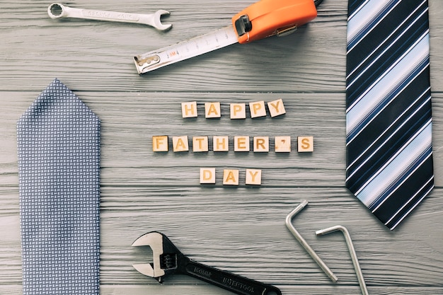 Accesorios masculinos cerca de instrumentos y felices palabras del día del padre.