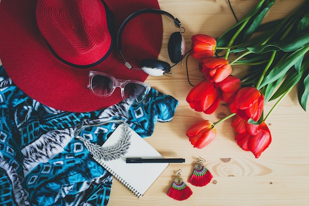 Accesorios de mujer y tulipanes rojos en mesa