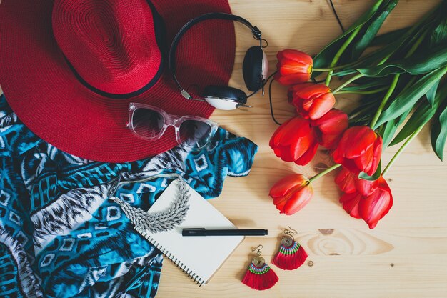 Accesorios de mujer y tulipanes rojos en mesa