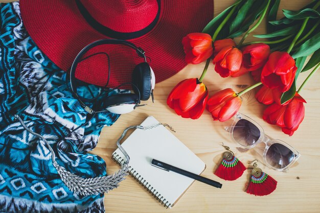 Accesorios de mujer y tulipanes rojos en mesa