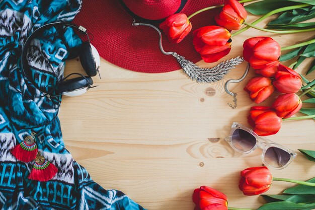 Accesorios de mujer y tulipanes rojos en mesa