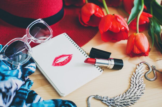 Accesorios de mujer y tulipanes rojos en mesa