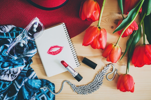 Accesorios de mujer y tulipanes rojos en mesa