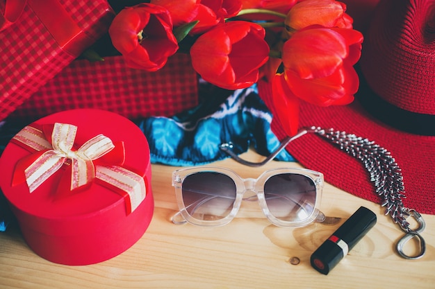 Accesorios de mujer y tulipanes rojos en mesa