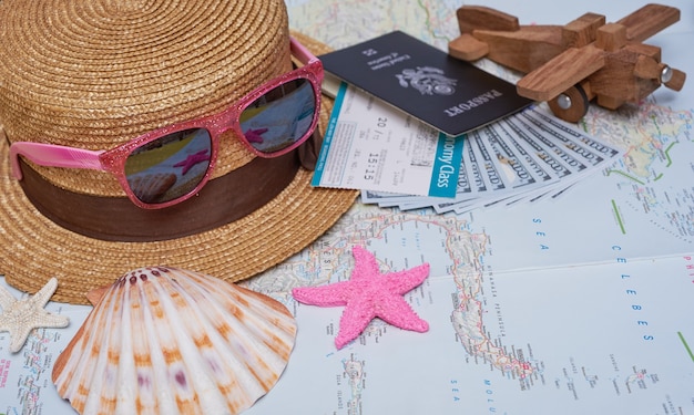 Accesorios para viajeros planos con hoja de palma, cámara, sombrero, pasaportes, dinero, boletos de avión, aviones, mapa y gafas de sol. Concepto de vista superior, viajes o vacaciones.