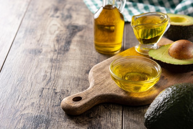 Aceite y aguacate fresco maduro sobre mesa de madera rústica