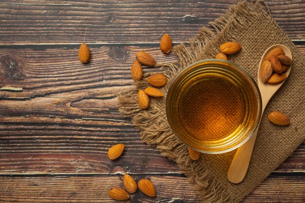 Aceite de almendras en botella sobre fondo de madera oscura.