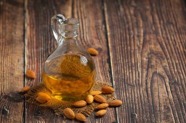 Aceite de almendras en botella sobre fondo de madera oscura.