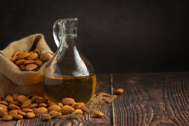 Aceite de almendras en botella sobre fondo de madera oscura.