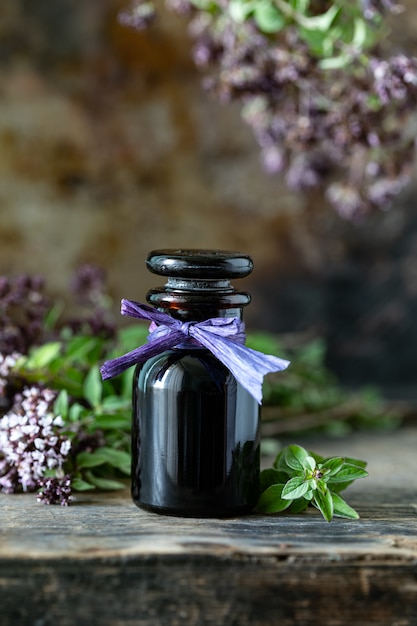 Foto gratuita aceite esencial de orégano en botella de vidrio sobre fondo de madera. copia espacio