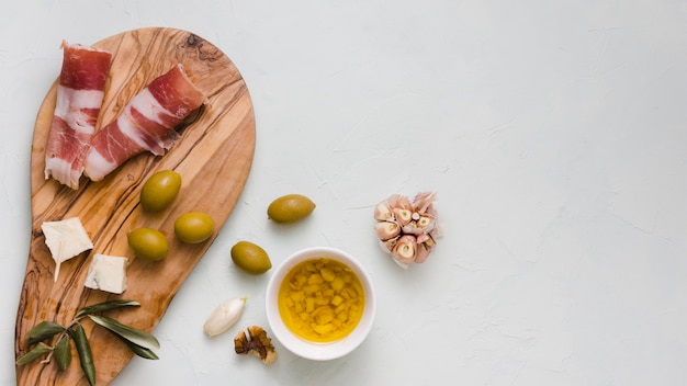 Aceite de oliva infundido; Olivos; club de ajo; Queso y tocino aislados sobre fondo blanco