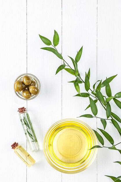 Aceite de oliva y rama de olivo en la mesa de madera