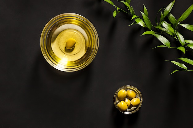 Aceite de oliva y rama de olivo en la mesa de madera