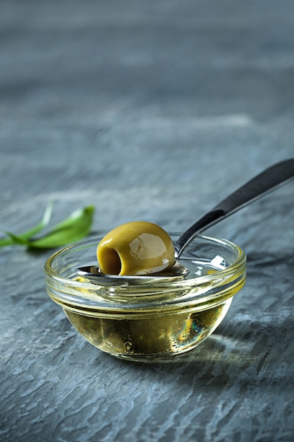 Aceite de oliva y rama de olivo en mesa de madera