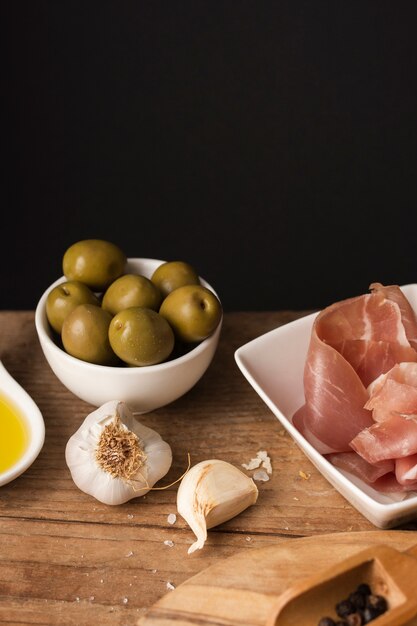 Aceitunas de alto ángulo y jamón en tabla de cortar