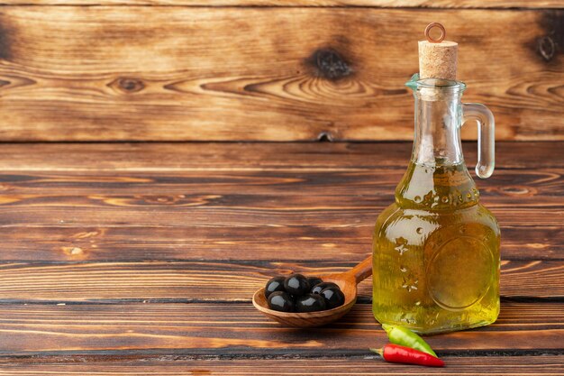 Aceitunas y botella de aceite de oliva sobre fondo de madera