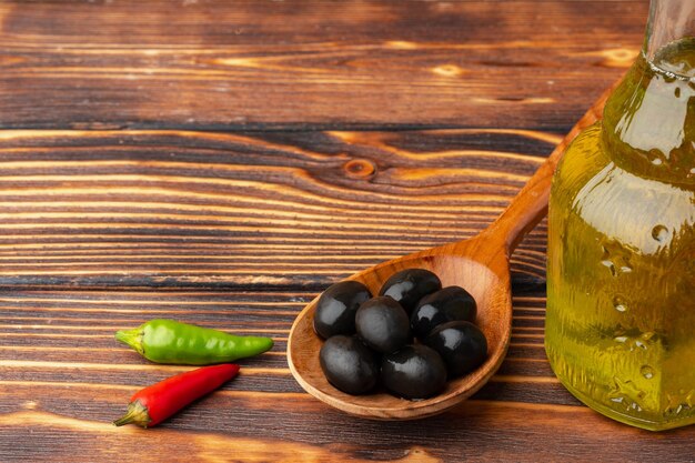 Aceitunas y botella de aceite de oliva sobre fondo de madera