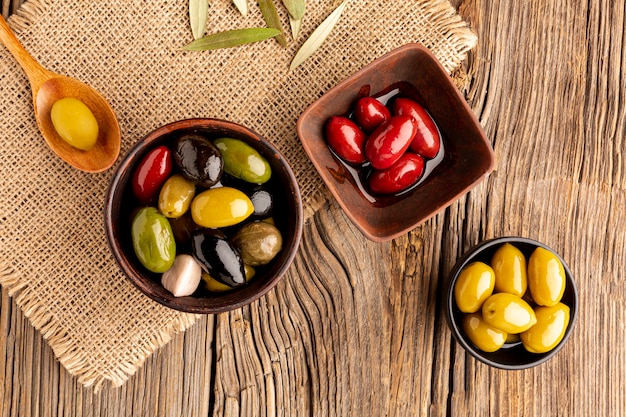 Aceitunas en cuencos y cuchara de madera sobre material textil.