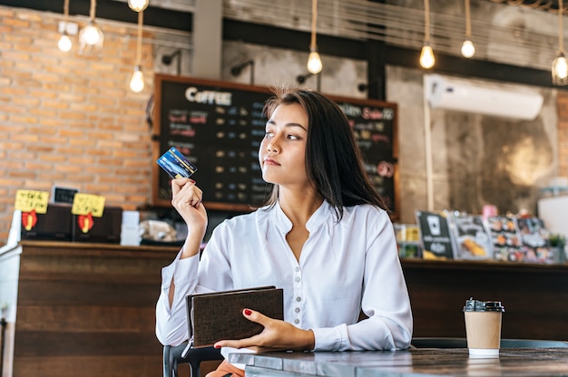 Se aceptan tarjetas de crédito de una cartera marrón para pagar los productos en pedidos de café.