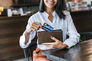 Foto gratuita aceptar tarjetas de crédito de una cartera marrón para pagar los bienes