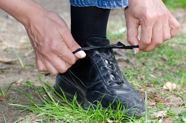 Acercamiento de un hombre atando sus cordones de los zapatos mientras está de pie sobre el césped