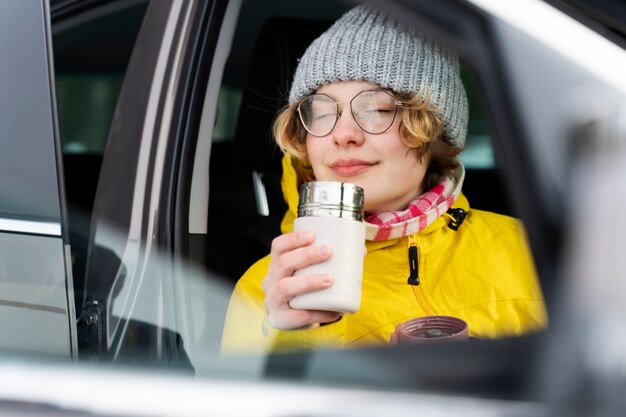 Acercamiento a una mujer disfrutando de una bebida caliente durante un viaje de invierno