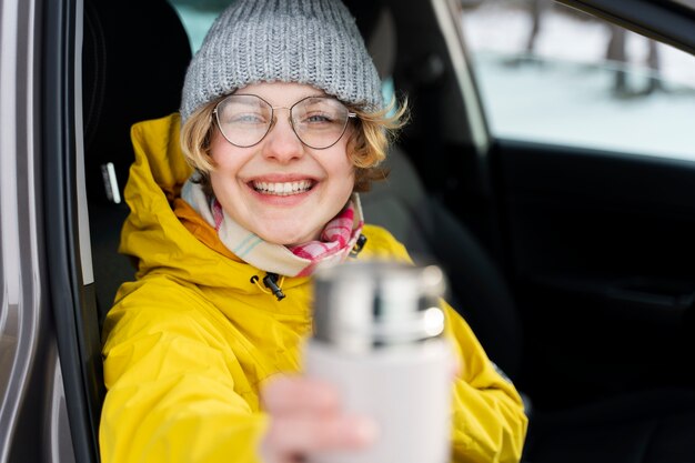 Acercamiento a una mujer disfrutando de una bebida caliente durante un viaje de invierno