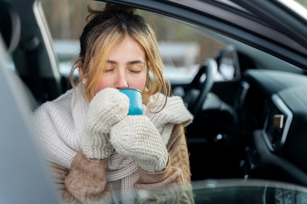 Acercamiento a una mujer disfrutando de una bebida caliente durante un viaje de invierno
