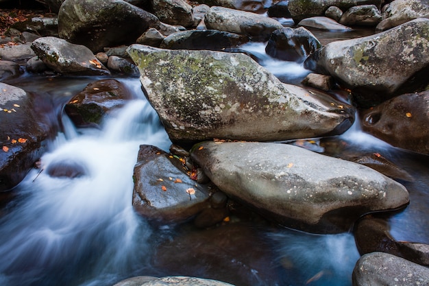 Acercamiento de las rocas en el flujo en cascada del río en un día frío