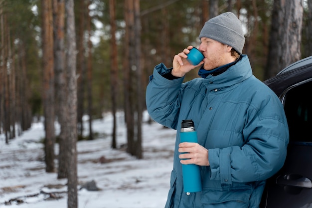 Acercarse al hombre disfrutando de una bebida caliente durante un viaje de invierno