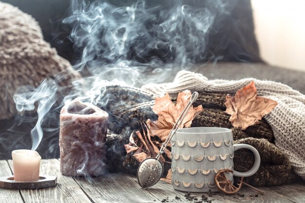 Acogedor desayuno de mañana de otoño en la cama todavía escena de la vida. Taza humeante de café caliente, té de pie junto a la ventana.