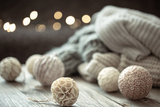 Acogedor fondo navideño con adornos navideños y elemento tejido sobre un fondo borroso.