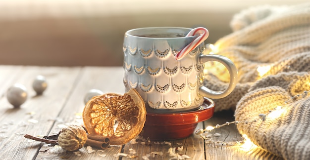 Acogedor fondo navideño con una taza, elemento de punto, estado de ánimo invernal, comodidad en el hogar.