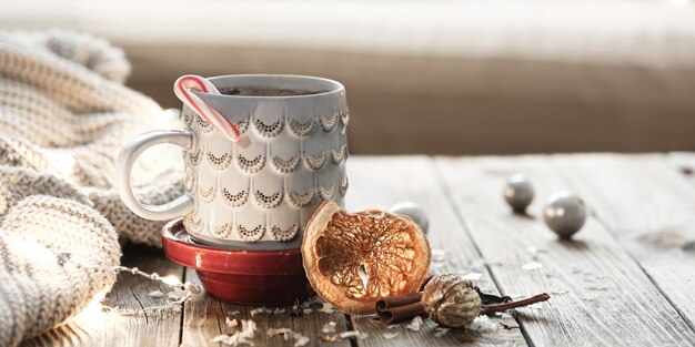 Acogedor fondo navideño con una taza, elemento de punto, estado de ánimo invernal, comodidad en el hogar.