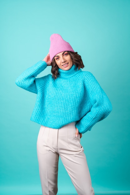 Acogedor retrato de una mujer joven con un suéter azul de punto y un sombrero rosa con maquillaje brillante