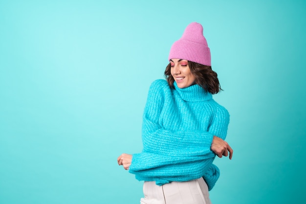 Foto gratuita acogedor retrato de una mujer joven con un suéter azul de punto y un sombrero rosa con maquillaje brillante