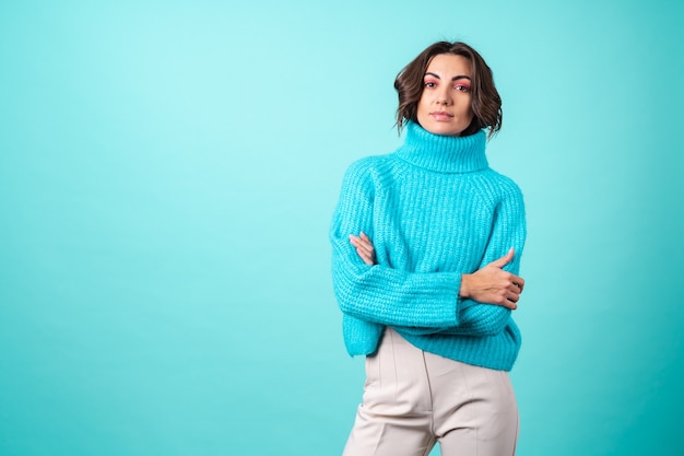 Acogedor retrato de una mujer joven con un suéter azul tejido y maquillaje rosa brillante en turquesa