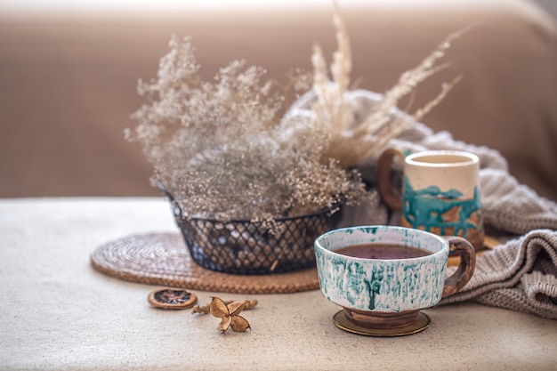 Acogedora composición casera con una hermosa taza de té de cerámica sobre la mesa. Elementos decorativos en el interior.