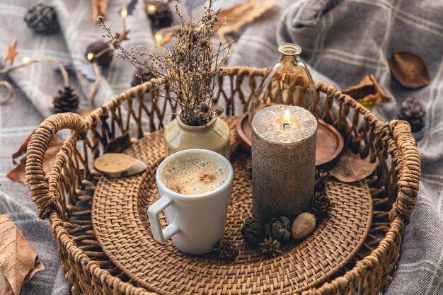 Acogedora composición casera con una taza de café, una vela y detalles decorativos.