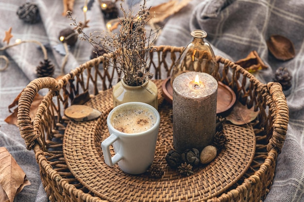 Acogedora composición casera con una taza de café, una vela y detalles decorativos.