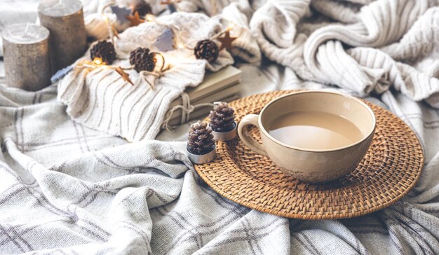 Acogedora composición otoñal con una gran taza de café en la cama