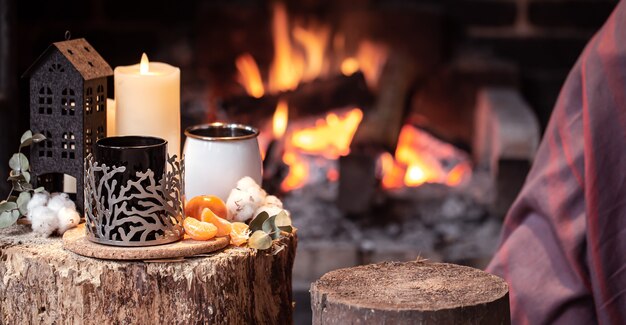 Acogedora composición con una taza, vela y mandarinas de un espacio de copia de chimenea ardiente.