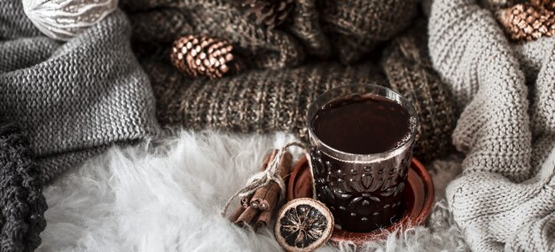 Acogedora mañana de Navidad con una taza de té en la cama. Escena de naturaleza muerta con suéteres.