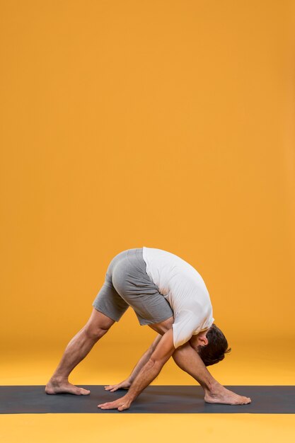 Actitud practicante de la yoga del hombre en la estera