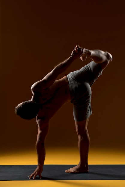 Actitud practicante de la yoga del hombre en la estera