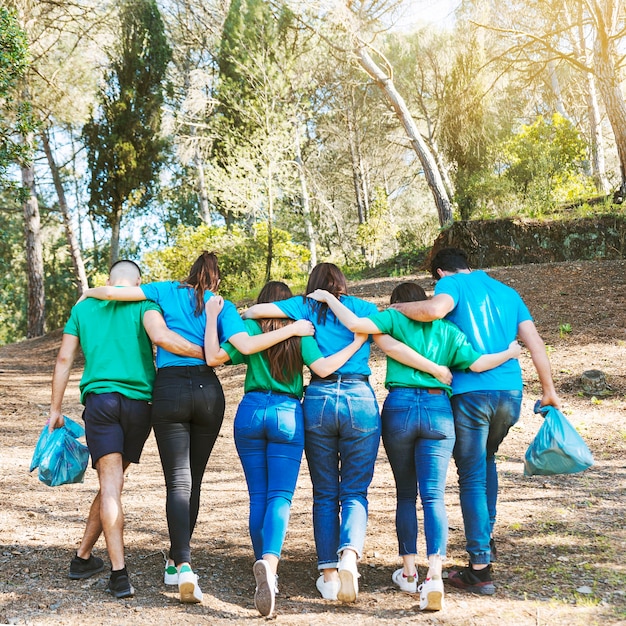 Activistas abrazándose caminando con bolsas de basura en el bosque