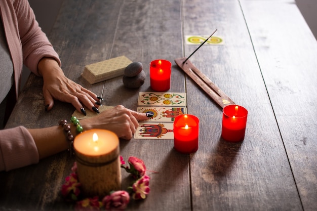 Adivino leyendo un futuro por cartas del tarot en mesa rústica